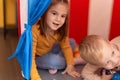 Adorable girl and boy playing with cars inside circus tent at kindergarten