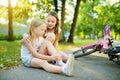 Adorable girl comforting her little sister after she fell off her bike at summer park. Child getting hurt while riding a bicycle Royalty Free Stock Photo