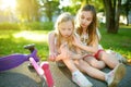 Adorable girl comforting her little sister after she fell off her scooter at summer park. Child getting hurt while riding a kick s Royalty Free Stock Photo