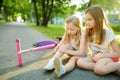 Adorable girl comforting her little sister after she fell off her scooter at summer park. Child getting hurt while riding a kick s Royalty Free Stock Photo