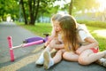 Adorable girl comforting her little sister after she fell off her scooter at summer park. Child getting hurt while riding a kick Royalty Free Stock Photo