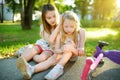 Adorable girl comforting her little sister after she fell off her scooter at summer park. Child getting hurt while riding a kick Royalty Free Stock Photo