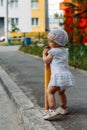 Adorable girl having fun on summer day. a little girl stands on the transition path and clings to the fence, pipe