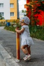 Adorable girl having fun on summer day. a little girl stands on the transition path and clings to the fence, pipe