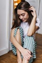 Adorable girl with lightly-tanned skin sitting on the floor at home. Indoor shot of blissful caucas