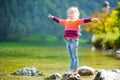 Adorable girl playing by Konigssee lake in Germany on warm summer day. Cute child having fun feeding ducks and throwing stones int Royalty Free Stock Photo