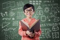 Adorable girl reads book near the blackboard Royalty Free Stock Photo