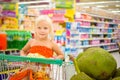 Adorable girl in shopping cart looks at giant jack fruits on box Royalty Free Stock Photo