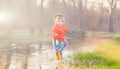 Adorable girl splashing puddle water in forest