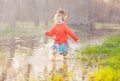 Adorable girl splashing puddle water in forest