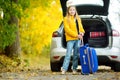 Adorable girl with a suitcase ready to go on vacations with her parents. Child looking forward for a road trip or travel. Autumn b