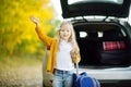 Adorable girl with a suitcase ready to go on vacations with her parents. Child looking forward for a road trip or travel. Autumn b Royalty Free Stock Photo