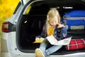 Adorable girl with a suitcase ready to go on vacations with her parents. Child looking forward for a road trip or travel. Autumn b Royalty Free Stock Photo