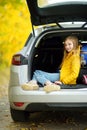 Adorable girl with a suitcase ready to go on vacations with her parents. Child looking forward for a road trip or travel. Autumn b Royalty Free Stock Photo