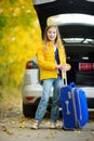 Adorable girl with a suitcase ready to go on vacations with her parents. Child looking forward for a road trip or travel. Autumn b