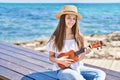 Adorable girl tourist smiling confident playing ukulele at seaside Royalty Free Stock Photo