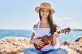 Adorable girl tourist smiling confident playing ukulele at seaside Royalty Free Stock Photo