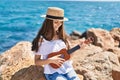 Adorable girl tourist smiling confident playing ukulele at seaside Royalty Free Stock Photo