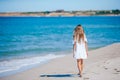 Back view of adorable little girl with long hair in white dress walking on tropical beach vacation Royalty Free Stock Photo