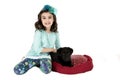 Adorable girl wearing blue outfit holding black puppy Royalty Free Stock Photo