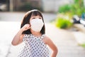 Adorable girl wearing a medical face mask goes for a walk outside. Happy child looked up and was questioning something.