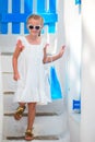 Adorable girl in white dress at street of typical greek traditional village with white walls and colorful doors in Royalty Free Stock Photo