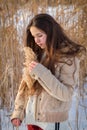 Adorable girl at winter landscape holding a reed stem