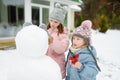 Adorable girls building a snowman in the backyard. Cute children playing in a snow. Winter activities for kids Royalty Free Stock Photo