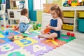 Adorable girls student cutting paper playing with dinosaur toy at kindergarten Royalty Free Stock Photo