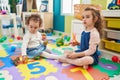 Adorable girls student cutting paper playing with dinosaur toy at kindergarten Royalty Free Stock Photo