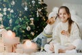 Adorable glad female child drinks milk and eats cookies, has wonderful time together with favourite dog, receives kiss from pet, Royalty Free Stock Photo