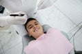 Adorable handsome brave preadolescent boy in dentist`s chair smiles toothy smile looking at camera and waiting for dental Royalty Free Stock Photo
