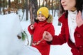 Adorable handsome child, preadolescent Caucasian boy in red down jacket making a snowman, enjoying active weekend pastime with his