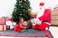 Adorable happy African American little girl child and Santa Santa Claus under decorative Christmas tree, Santa Claus giving a Royalty Free Stock Photo