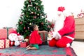 Adorable happy African American little girl child and Santa Santa Claus under decorative Christmas tree, Santa Claus giving a Royalty Free Stock Photo