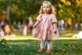 adorable happy baby girl throwing the fallen leaves up, playing in the autumn park Royalty Free Stock Photo