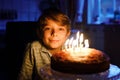 Adorable happy blond little kid boy celebrating his birthday. Child blowing candles on homemade baked cake, indoor Royalty Free Stock Photo