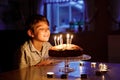 Adorable happy blond little kid boy celebrating his birthday. Child blowing candles on homemade baked cake, indoor Royalty Free Stock Photo