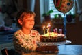 Adorable happy blond little kid boy celebrating his birthday. Child blowing seven candles on homemade baked cake, indoor Royalty Free Stock Photo