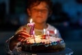 Adorable happy blond little kid boy celebrating his birthday. Child blowing seven candles on homemade baked cake, indoor Royalty Free Stock Photo