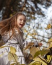Adorable happy child girl throwing the fallen leaves up, playing in the autumn park Royalty Free Stock Photo
