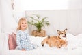 Adorable happy child in pajamas sitting with corgi dogs