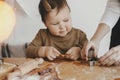 Adorable happy daughter and mother making together christmas cookies on messy table. Cute toddler girl helper with mom cutting Royalty Free Stock Photo