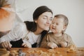 Adorable happy daughter and mother making together christmas cookies on messy table. Cute toddler girl helper with mom cutting Royalty Free Stock Photo