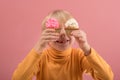 Adorable happy fair-haired boy smiling and holding yummy cupcakes in hands on pink background