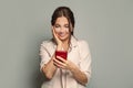 Adorable happy female model checking her news feed or messaging via social networks, using free wi-fi on mobile phone Royalty Free Stock Photo