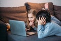 Adorable happy girl and boy using laptop and lying on sofa Royalty Free Stock Photo