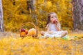 Adorable happy girl eating apple, playing in the autumn park on warm sunny weather. Cute child on maple leaves. Colorful Royalty Free Stock Photo