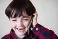 Adorable happy laughing little caucasian boy in plaid shirt talking by cell phone Royalty Free Stock Photo