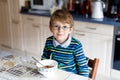 Happy little blond kid boy eating cereals for breakfast or lunch. Healthy eating for children. Royalty Free Stock Photo